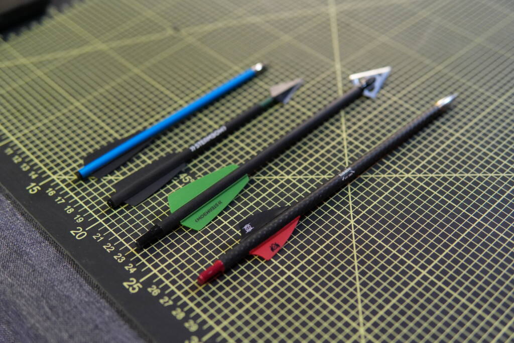 Size comparison of 6.2x162mm and 7.5x220mm crossbow bolts on cutting mat, showing length and diameter differences