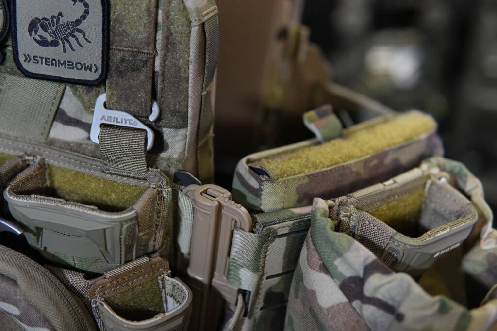 Close-up of an Agilite K Zero SF plate carrier with mounted Pincer triple magazine pouch and wide admin pouch, showing detailed MOLLE setup and side configuration.