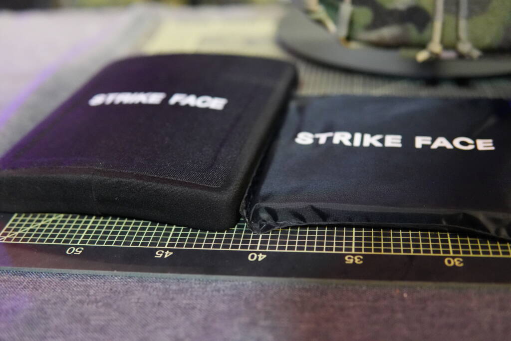 Two ballistic plates placed side by side on a cutting mat – on the left a thick hard NIJ III+ plate, on the right a thinner soft NIJ III+ plate, both labeled “Strike Face.”