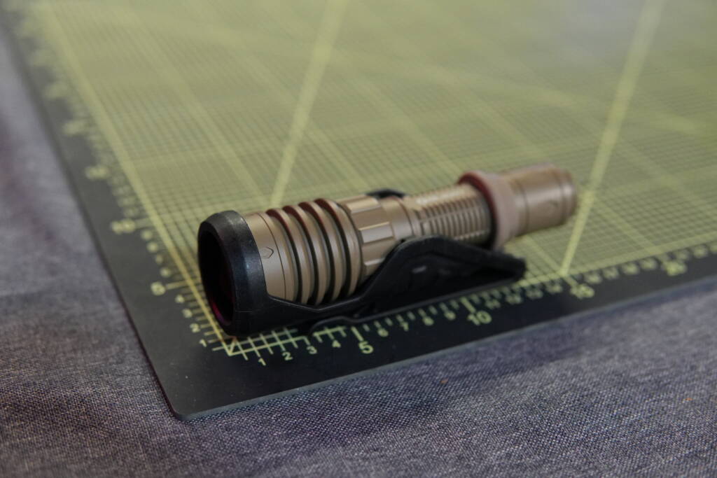 Olight Warrior X4 tactical flashlight secured in a rigid polymer MOLLE holster on a table.