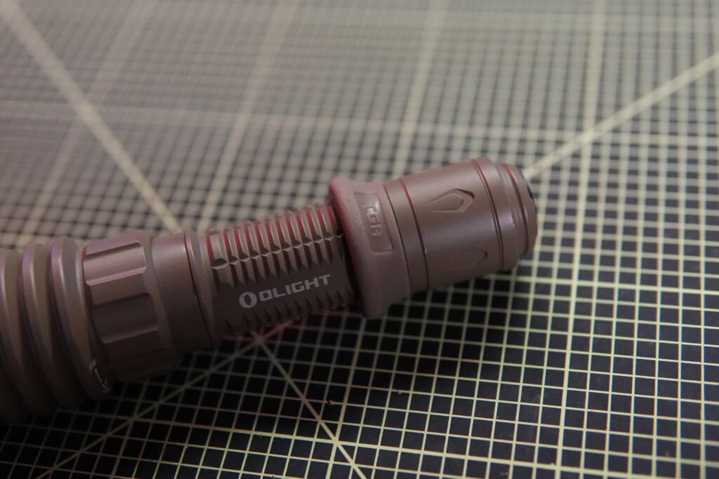 Olight Warrior X4 tactical flashlight showing textured grip surface and rubber ring for improved handling.