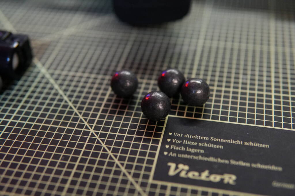 .68 caliber lead musket balls on a cutting mat, traditional black powder projectiles weighing about 30 g each.