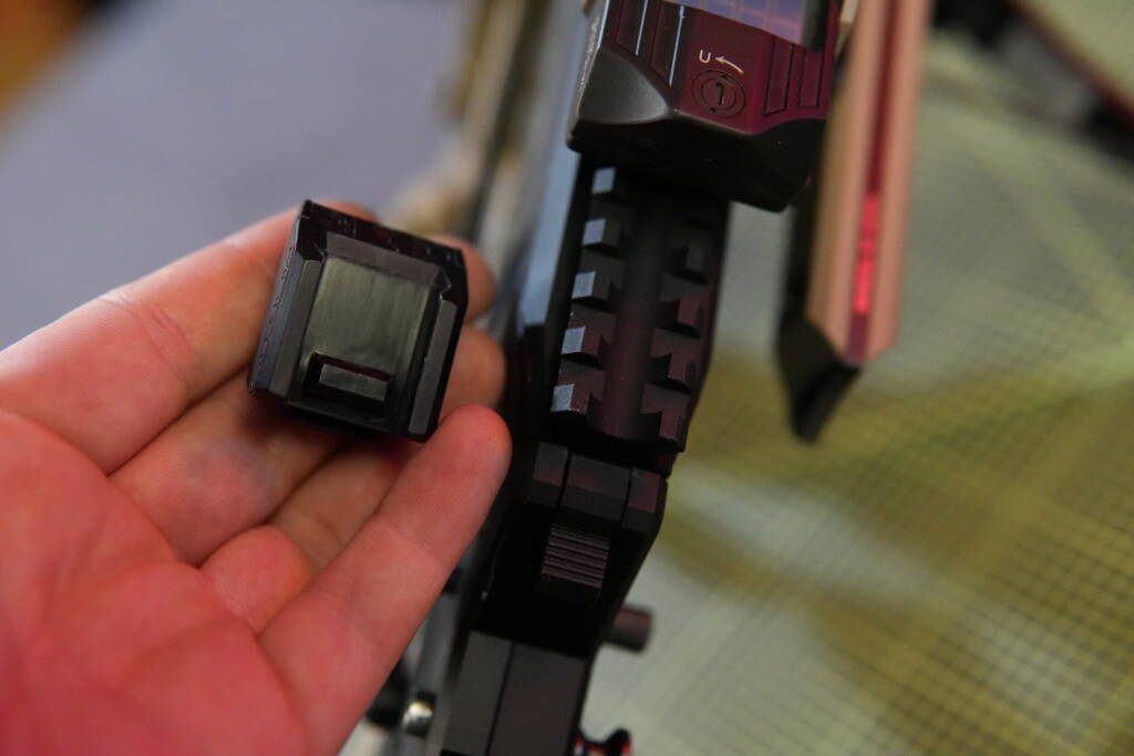 Mantis X10 sensor shown next to a Picatinny rail mount on a firearm platform.