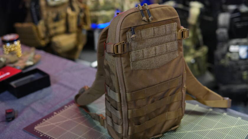 Helikon-Tex Guardian Small Pack tactical hydration backpack shown on a cutting mat with MOLLE webbing and shoulder straps visible.