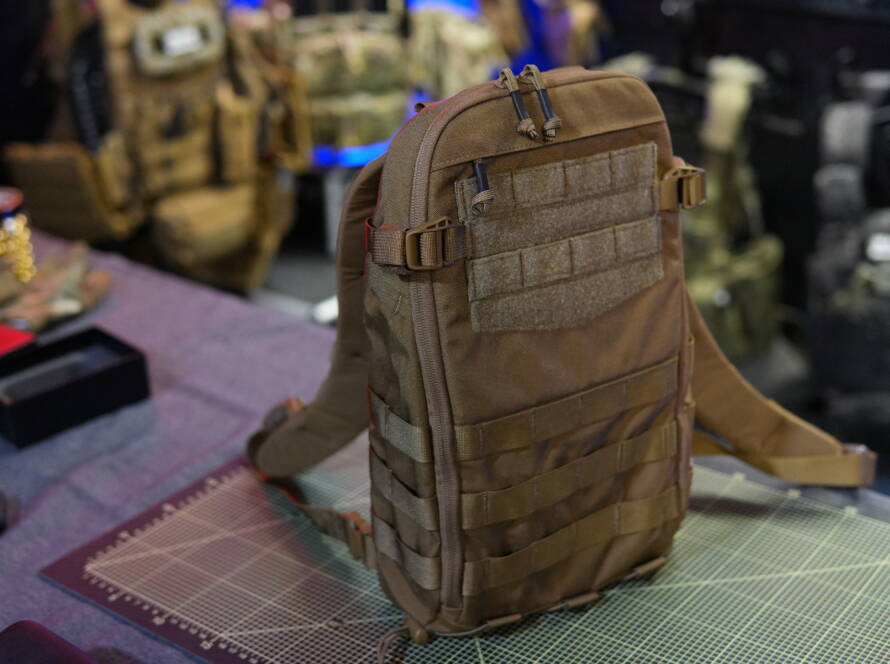 Helikon-Tex Guardian Small Pack tactical hydration backpack shown on a cutting mat with MOLLE webbing and shoulder straps visible.